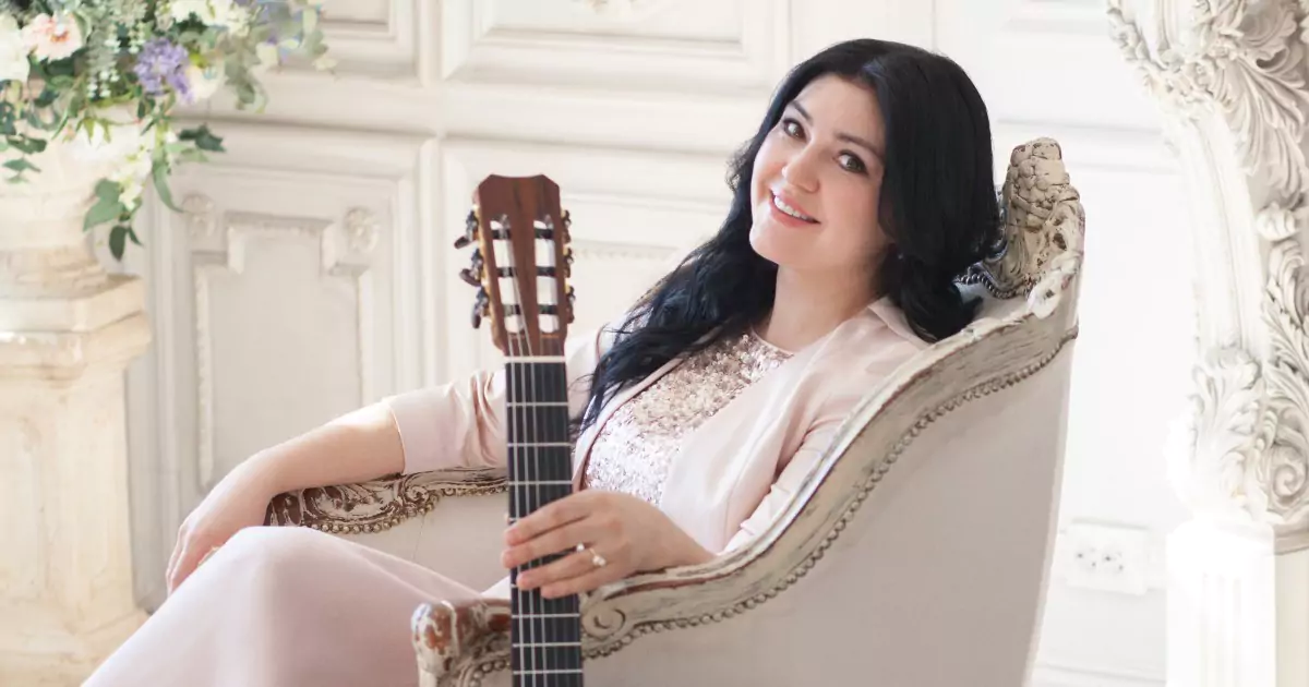Irina Kulikova seduta in poltrona con la chitarra