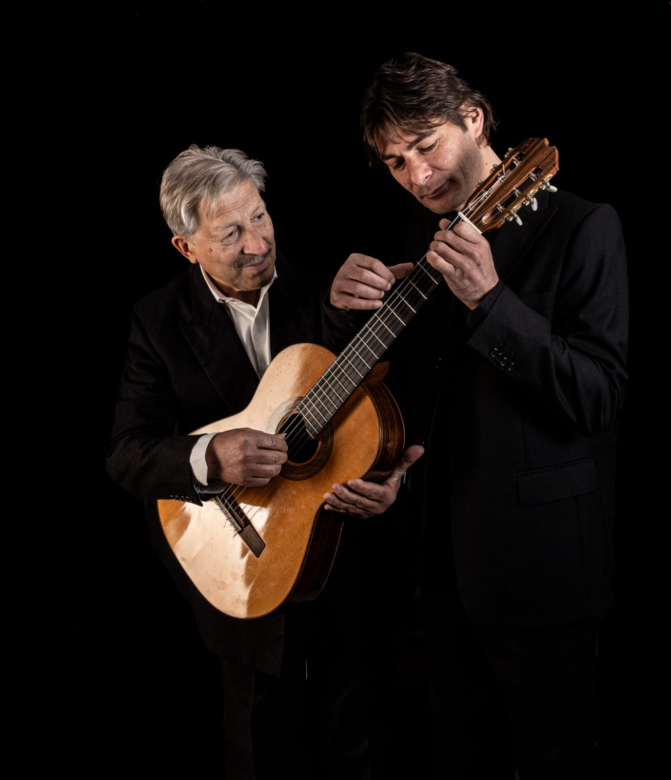 Nello e Simone Alessi con una chitarra su sfondo nero